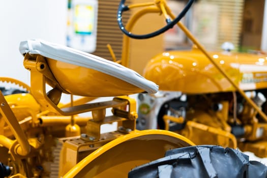 Small yellow tractor in an exhibition, closeup details, wheels