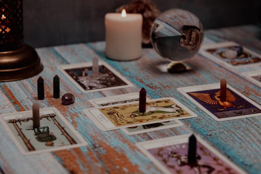 A tarot card reading session depicted with candles, crystals, and mystical accessories on a rustic wooden table