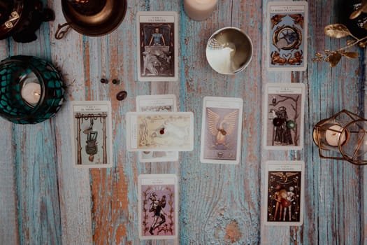 A dimly lit scene showing a spread of tarot cards, alongside crystals, candles, and a crystal ball on a rustic wooden table