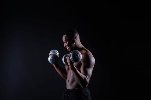 Young man with dumbbells good physique isolated on red black background. Strength and motivation