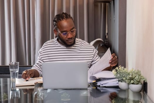 Young African American businessman spends his free time working from home on his laptop..