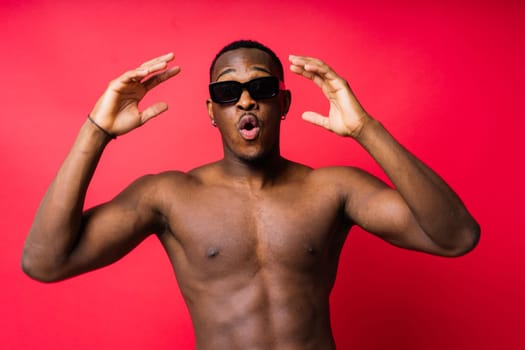 Portrait of athletic african american man topless smiling, yellow, red and black background