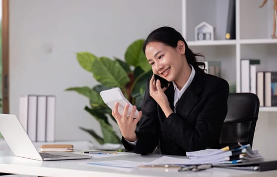 Beautiful accountant talking on the phone and calculating financial figures and calculating taxes for the company..