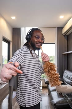 Playful African man in casual clothes Clean the dust or dirtiness of the room happily and have fun cleaning..