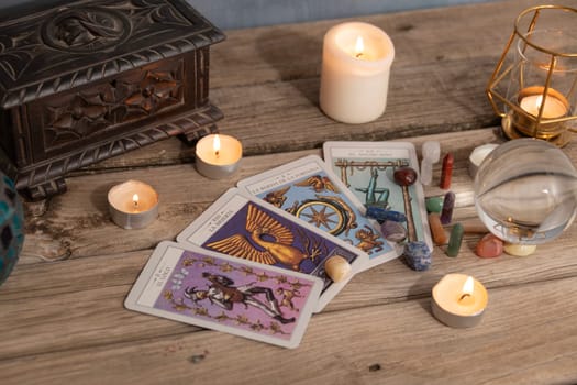 Close-up of a tarot card arrangement with a crystal ball and flickering candles on an aged wooden surface