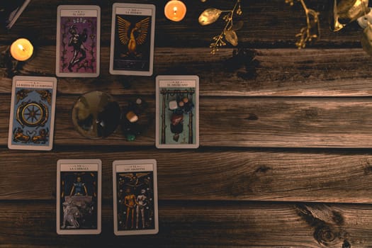 Tarot cards including The Fool and The Lovers alongside crystals and candles on a textured wooden table