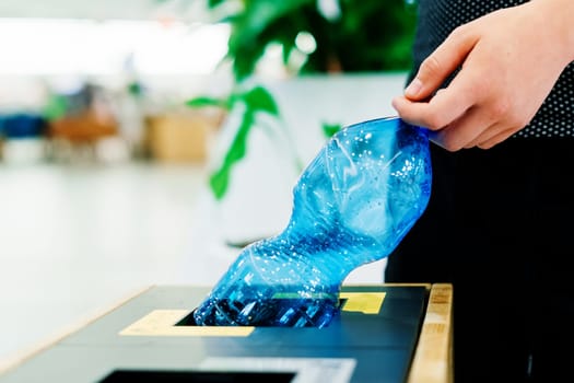 Hand of young man throwing plastic bottle in a recycling trash bin