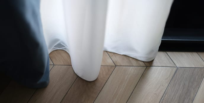 Beautiful white curtains indoors and wooden parquet floor closeup. Curtain design and floor concept