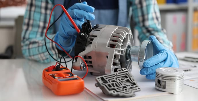 Automotive alternator repair test stator closeup with copper coil in workshop. Checking generator with multimeter concept