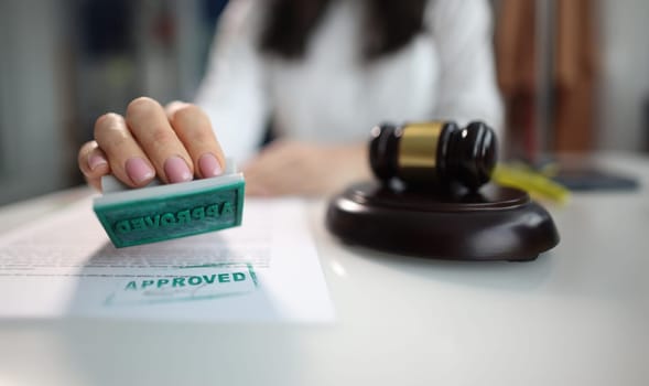 Business woman puts an approved seal on a closeup of document. Successful action holding or judgment concept