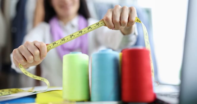 Seamstress holds tape measure in sewing workshop. Small business development concept and atelier opening