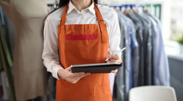 Dry cleaning administrator holds tablet with documents to sign. Laundry service concept