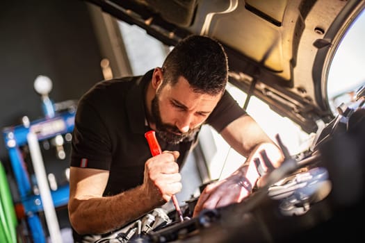 Milan, Italy 9 April 2024: Mechanic's hands delve into car engine under the hood, symbolizing repair and maintenance.