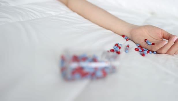 Woman hand after overdose of medical pills on bed. Medical consequences of abuse of sleeping pills concept