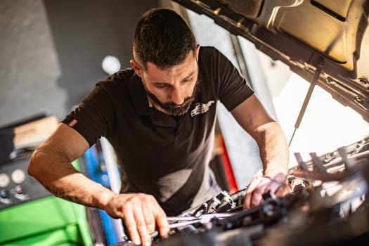 Milan, Italy 9 April 2024: Mechanic's hands delve into car engine under the hood, symbolizing repair and maintenance.