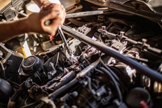 Milan, Italy 9 April 2024: Close-up of a mechanic's dirty hands while repairing a car engine, showcasing hard work.