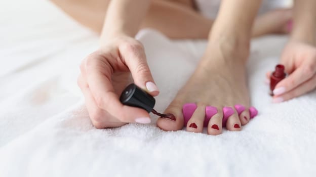 Woman makes herself pedicure on white background. Beautiful nail pedicure concept