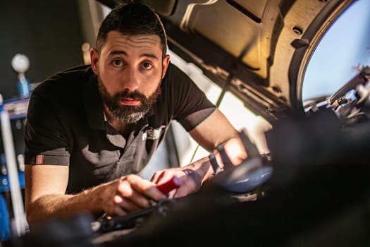 Milan, Italy 9 April 2024: Mechanic's hands delve into car engine under the hood, symbolizing repair and maintenance.