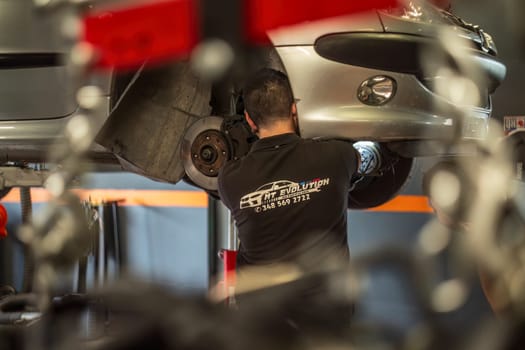 Milan, Italy 9 April 2024: Mechanic's hands delve into car engine under the hood, symbolizing repair and maintenance.