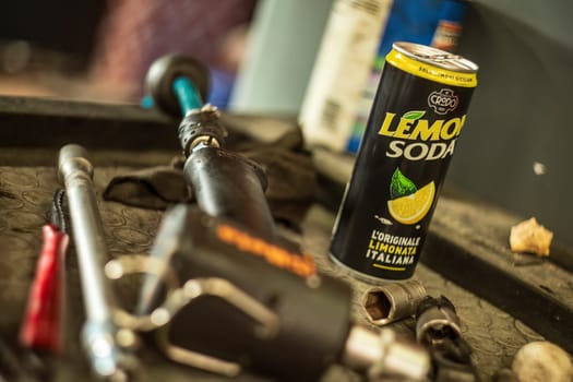 Milan, Italy 9 April 2024: A lemon soda can placed among various tools on a workshop bench.