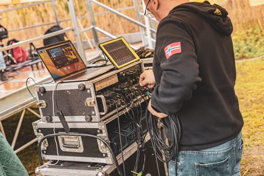 Milan, Italy 1 April 2024: A focused sound engineer at work, setting up equipment for a live performance, ensuring perfect audio quality.