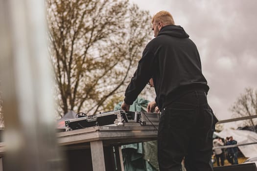 Milan, Italy 1 April 2024: A man stands confidently at a table with a DJ mixer, deftly manipulating knobs and sliders as he creates a seamless blend of beats.