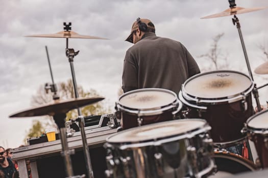 A dynamic man passionately drumming in front of a captivated audience during a live musical performance.