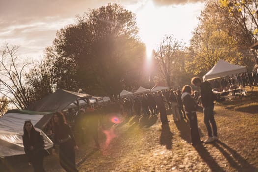 Milan, Italy 1 April 2024: A vibrant sunset rave party in a park, showcasing energetic silhouettes dancing.