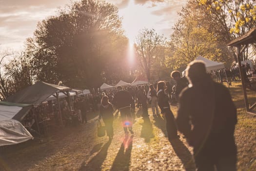 Milan, Italy 1 April 2024: A vibrant sunset rave party in a park, showcasing energetic silhouettes dancing.