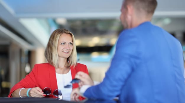 Smiling businesswoman communicates with a man in cafe. Acquaintance and business meeting concept