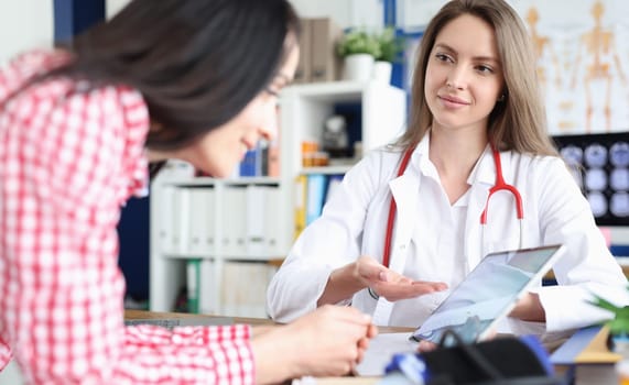 Doctor shows woman on tablet result of medical examination. Viewing ultrasound of baby fetus