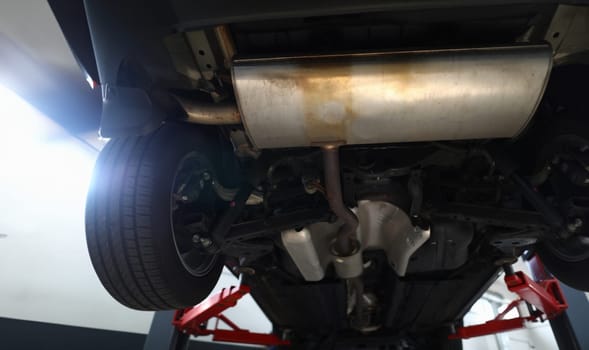 Bottom of car with muffler on lift. Car suspension service concept