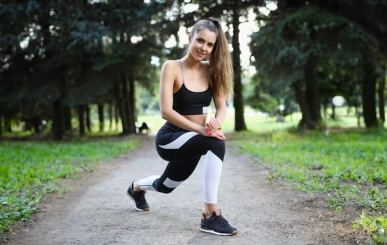 Young athletic woman doing exercises in park. Morning exercises on the street concept