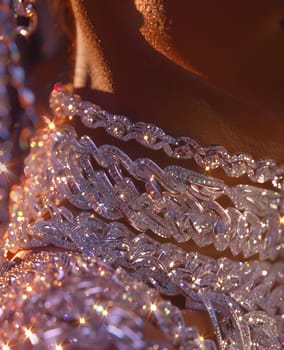 Closeup macro photography of a womans neck adorned with a wooden necklace and metal earrings, reflecting light like water drops on rock, highlighting the beauty of flesh and moisture