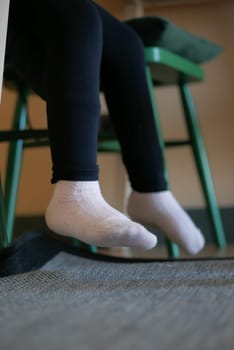 low angle view of a soft socks on kid feet sitting on a chair