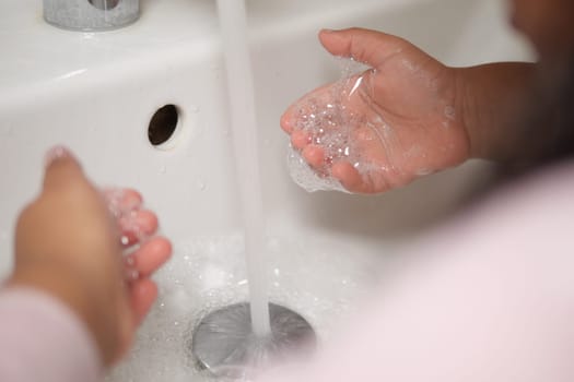 kid making a cleansing gesture with soap and water on hands.