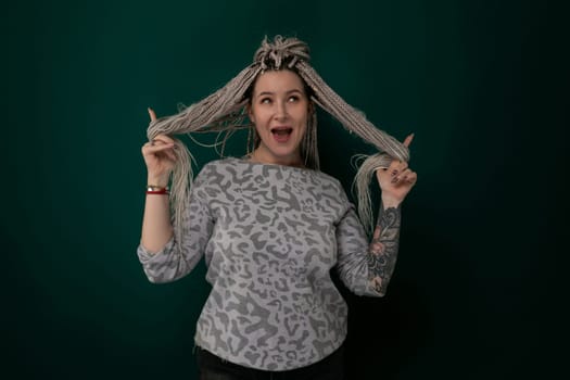 A woman is seen in the image holding her hair in front of her head, appearing to be adjusting or styling her hair. She seems focused on the task, with a determined expression on her face.