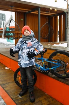 Boy in winter clothes took a break while riding a bike.