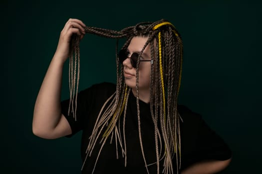 A woman with long, knotted dreadlocks on her head. She is looking off to the side, with a serene expression on her face. Her hair cascades down her back, showcasing the intricate texture of the dreadlocks.