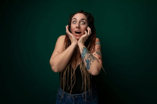 A woman with dreadlocks is shown covering her face with her hands. Her facial features are obscured, emphasizing a sense of privacy or introspection. The dreadlocks cascade down her shoulders, adding texture to the image.