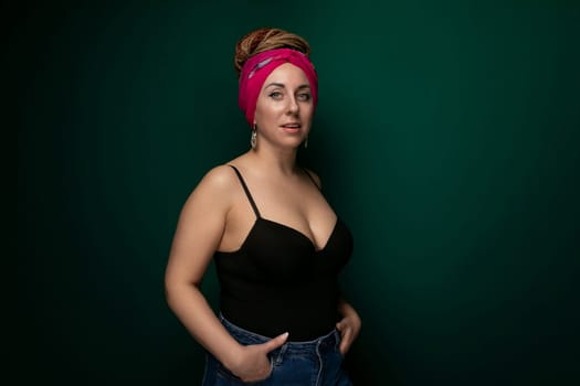 A woman wearing a pink headband is standing in front of a vibrant green wall. She appears to be posing for the camera, with a neutral expression on her face.