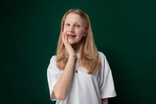 A young girl, possibly a teenager, is posing for a picture in front of a vibrant green background. She appears confident and is smiling for the camera.