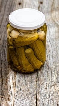 Close up of glass jar with pickles isolated. Preserved food concept, canned vegetables isolated in a rustic composition.