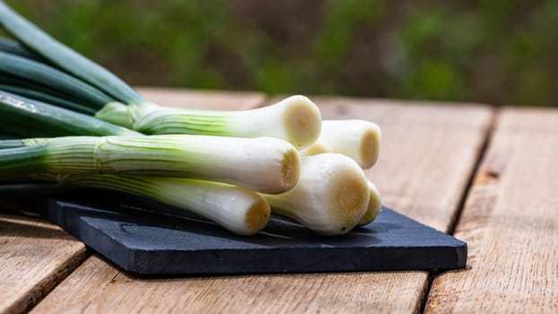 Close up of details of fresh green onions (scallion) on a cutting board isolated.