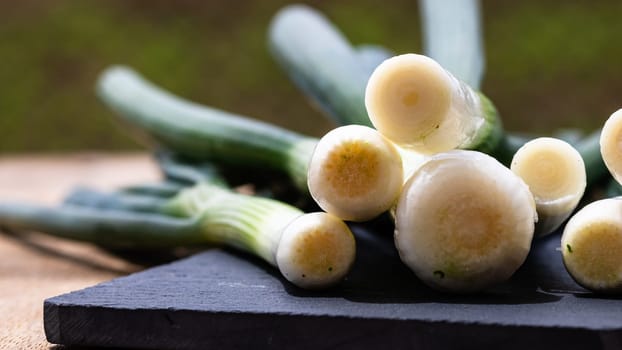 Close up of details of fresh green onions (scallion) on a cutting board isolated.