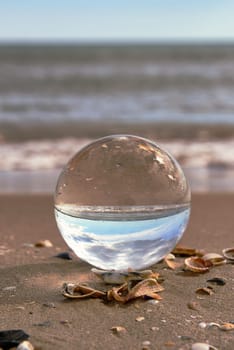 A beach landscape on a crystal ball. Photography techniques, sun, water, reflections, seashells, water, sun sun clear sky