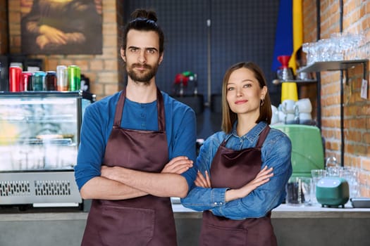 Small business team portrait of confident successful colleagues partners young man woman in aprons posing looking at camera at workplace in restaurant coffee shop cafeteria. Partnership teamwork work