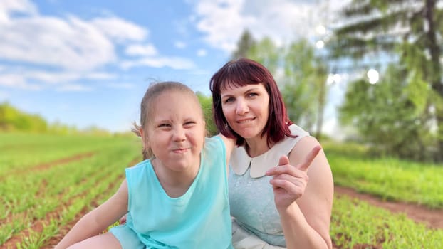 Happy mother and daughter enjoying rest, playing and fun on nature in green field. Woman and girl resting outdoors in summer or spring day