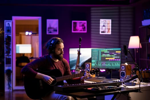 Skilled singer producer recording guitar tunes and adding piano key sounds, creating a beautiful song with mixing console and daw software on pc. Acoustical engineer working with electronic gear.