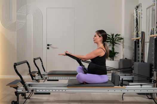 Pregnant woman doing Pilates exercises on a reformer machine